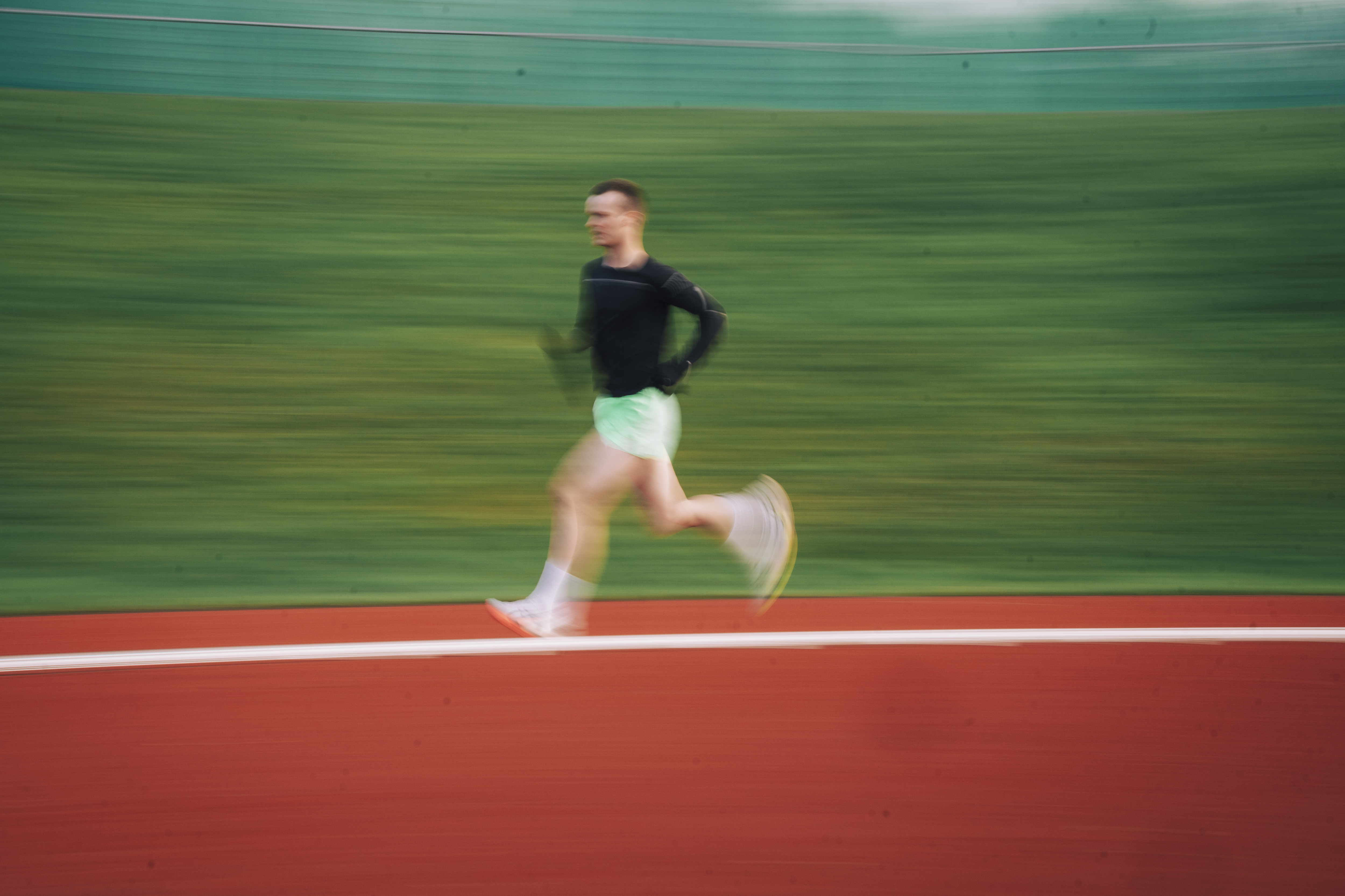 An athlete running around a track, photographed with motion blur.